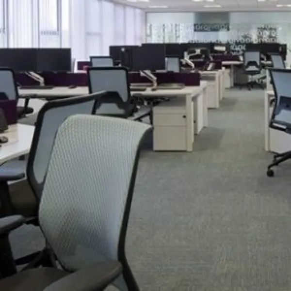 Bright empty office with white desks and grey chairs